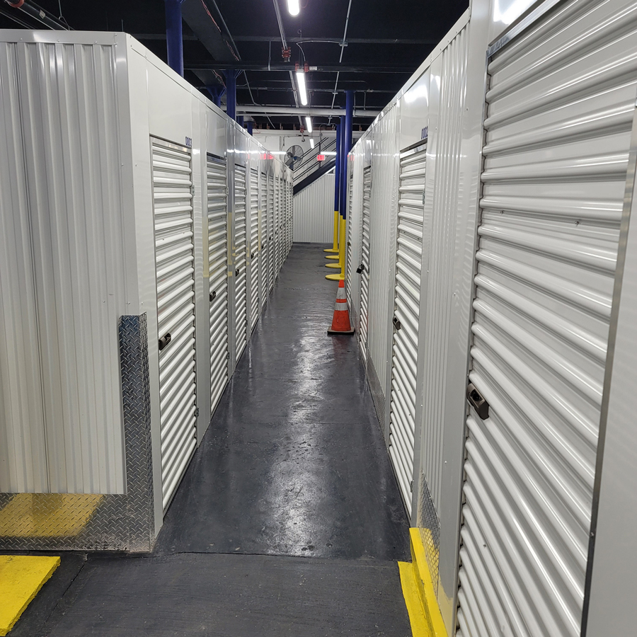 Bright interior hallway lined with roll-up storage unit doors at StorageBlue Paterson